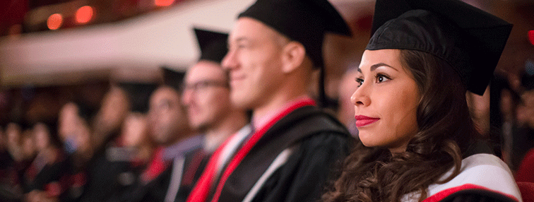 Photo of McMaster Students sitting in academic regalia during a convocation ceremony.